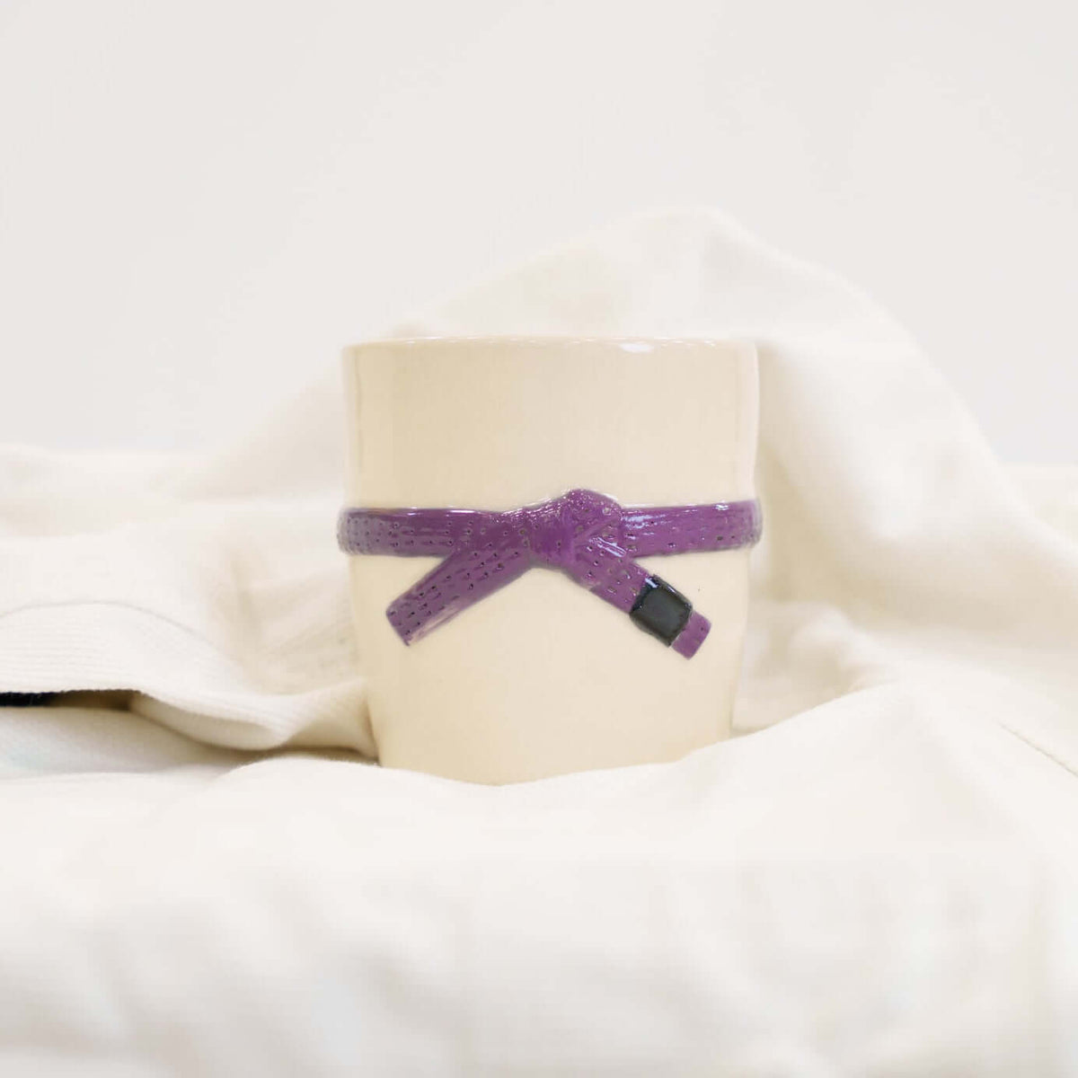 A cream colored mug with a purple brazilian jiu jitsu belt design