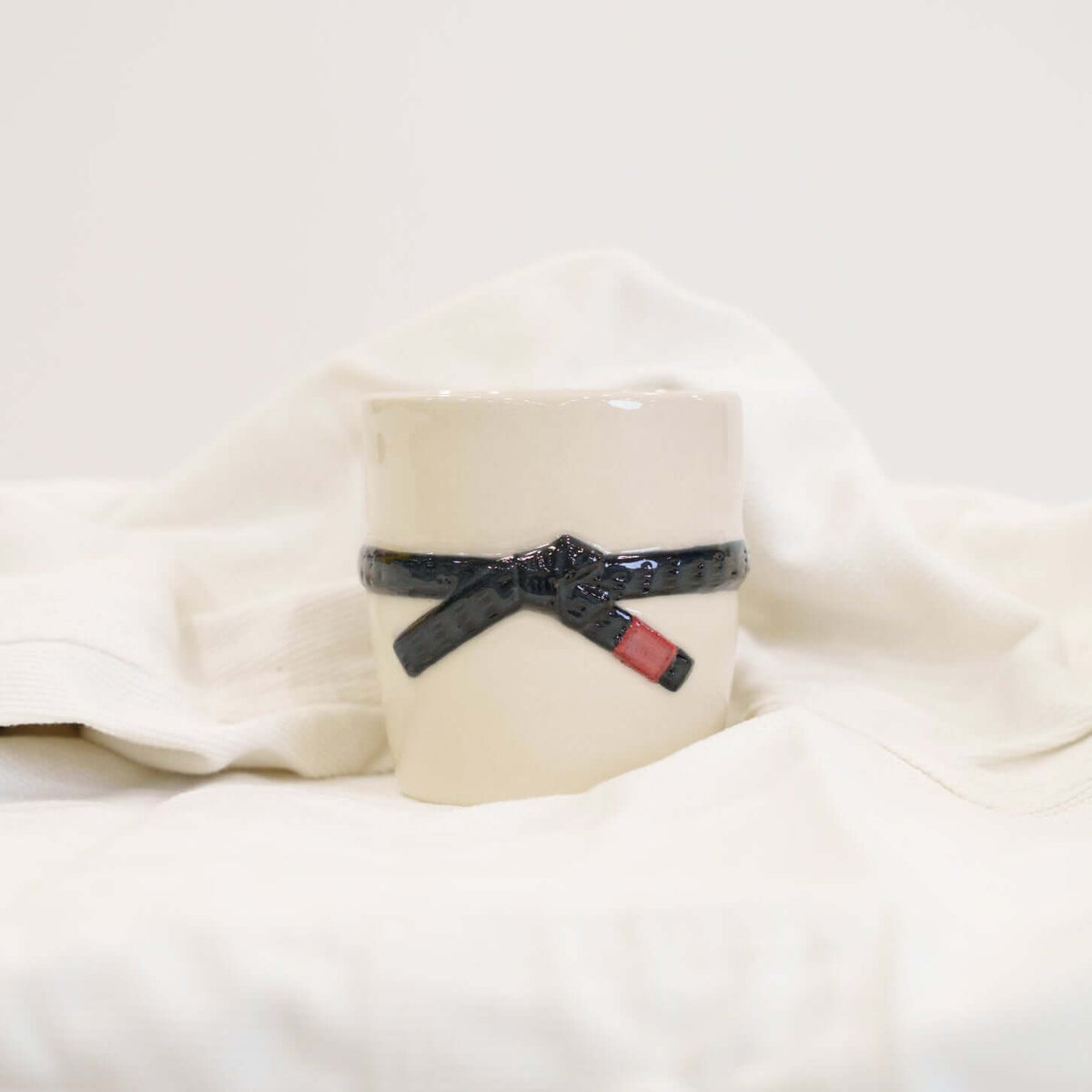 A cream colored mug with a black brazilian jiu jitsu belt design