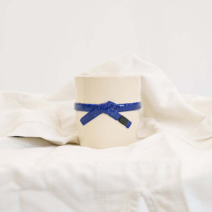 A cream colored mug with a blue brazilian jiu jitsu belt design