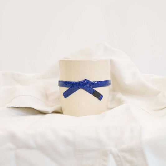 A cream colored mug with a blue brazilian jiu jitsu belt design