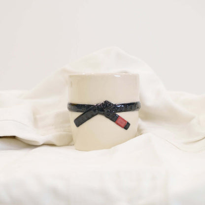 A cream colored mug with a black brazilian jiu jitsu belt design